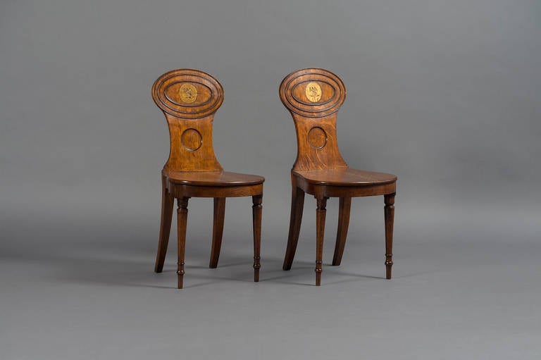 Pair excquiste oak hall chairs circa 1800. The back ornamented with oval astragal mouldings and decorated with a family crest