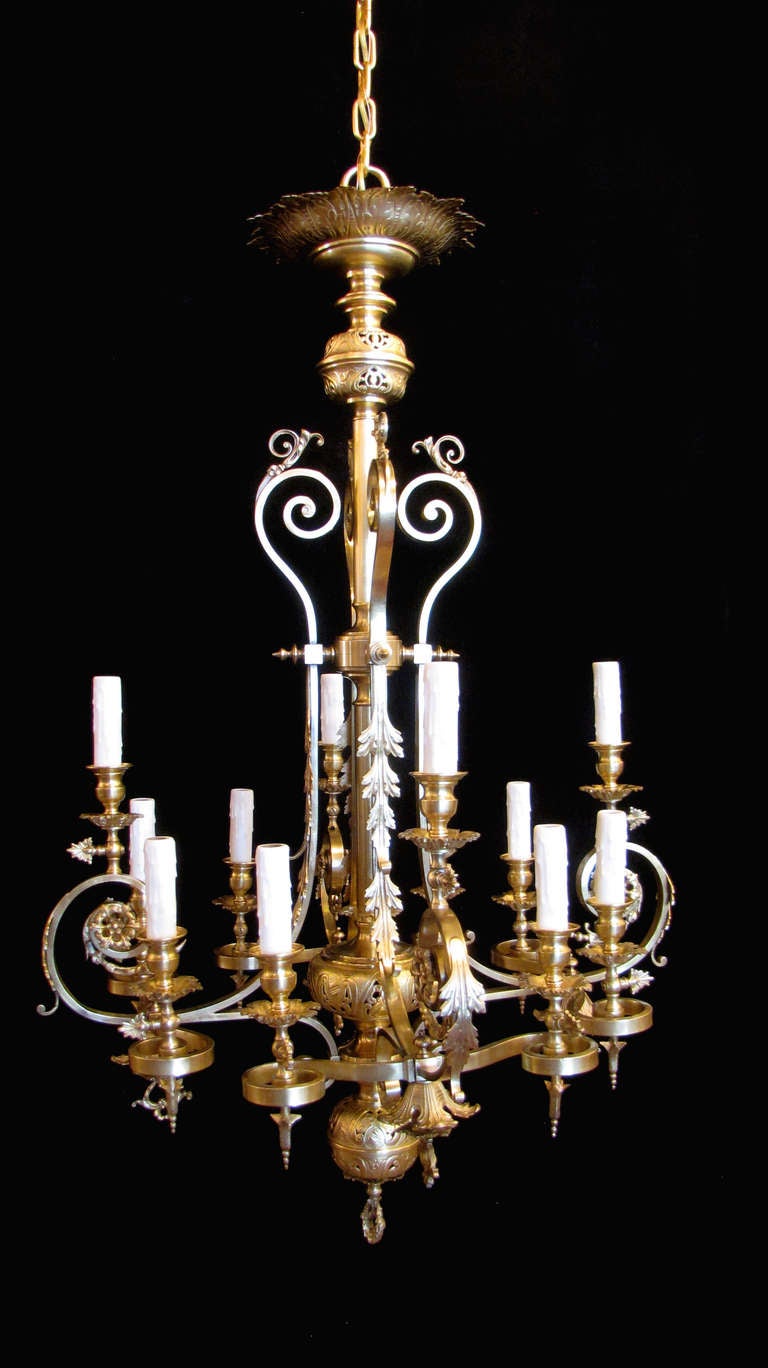 This chandelier is a stunning bronze fixture ornamented with acanthus leaves and rosettes. It features scroll form arms and pierced spheres on the stem, crowned with a leafy corona. It was originally gas, evidenced by the trefoil gas-cocks, and has