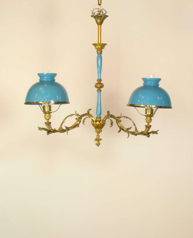 This is a Louis XV style two light chandelier with bronze dore leaf detail. Stem pieces and shades are original azure blue colored glass.