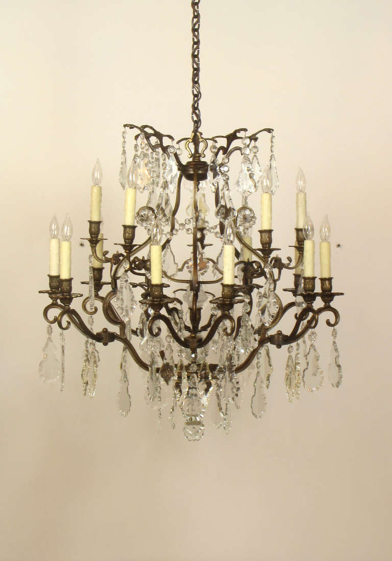 This chandelier has a patinated bronze cage form frame, and large pendelogue style crystals.  There are fifteen lights.