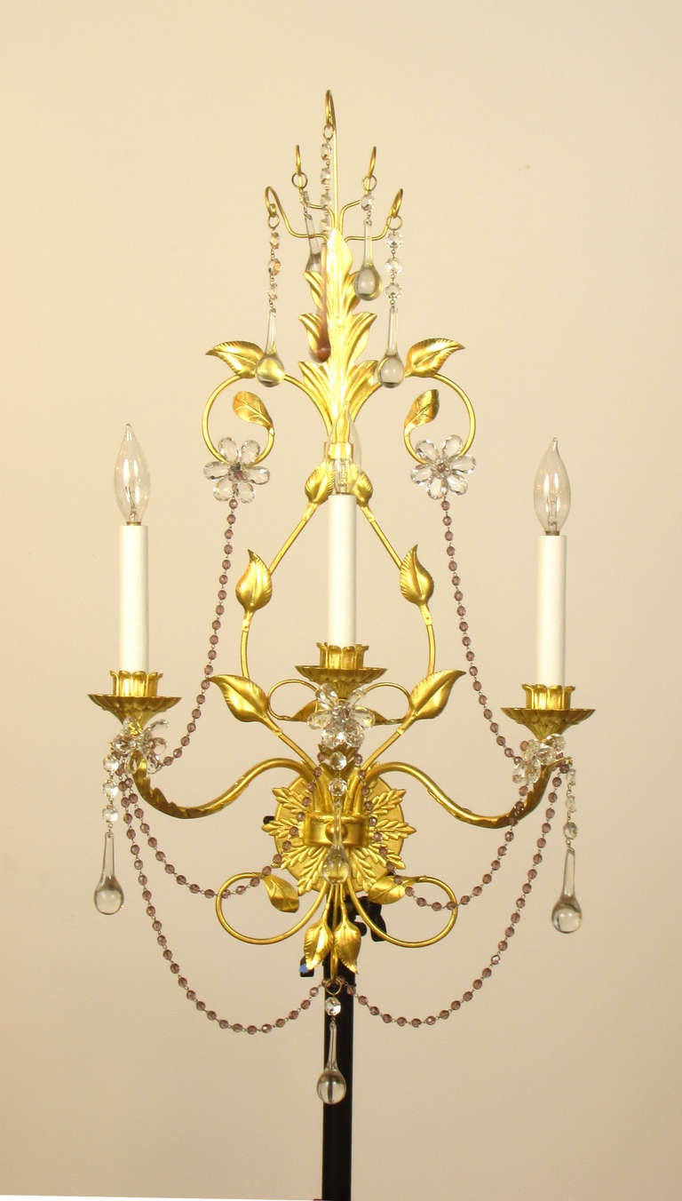 A set of 3 large gilt metal and crystal sconces with delicate metal work. The crystals are clear and amethyst, with flower ornaments, and draping crystal bead chain. The gilt finish has been completely restored.  Attributed to E. F. Caldwell.