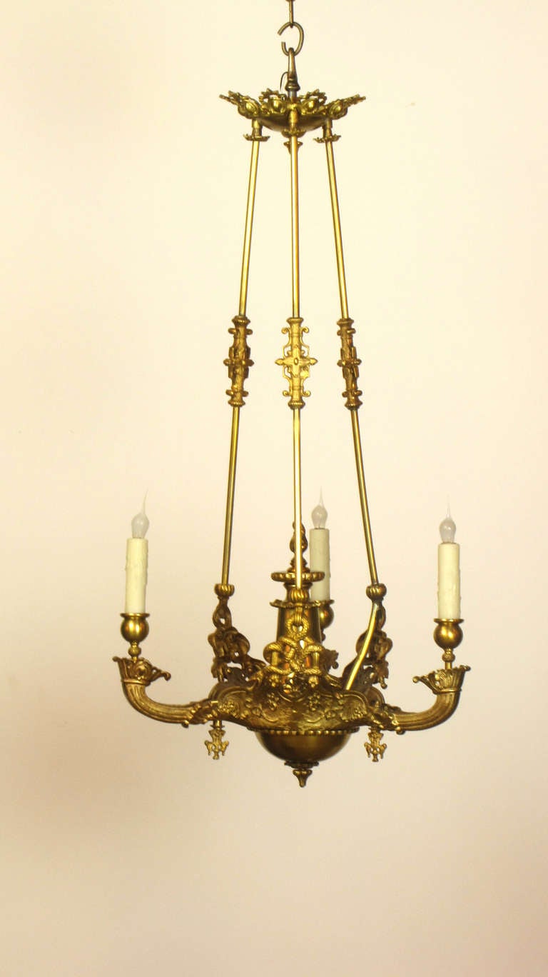 This is an early gasolier in the shape of an oil chandelier with snake details. it is suspended from the canopy by three rods.  Attributed to Cornelius & Company