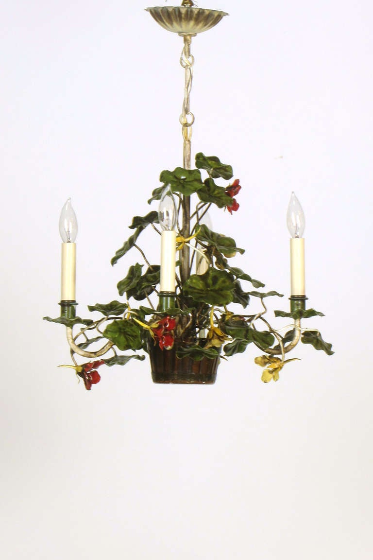 This is a petite chandelier perfect for a casual dining or sunroom.  It is in the form of a potted nasturtium plant with flowers in shades of yellow, red and orange, and an antiqued finish on the leaves and stem.  There are four lights