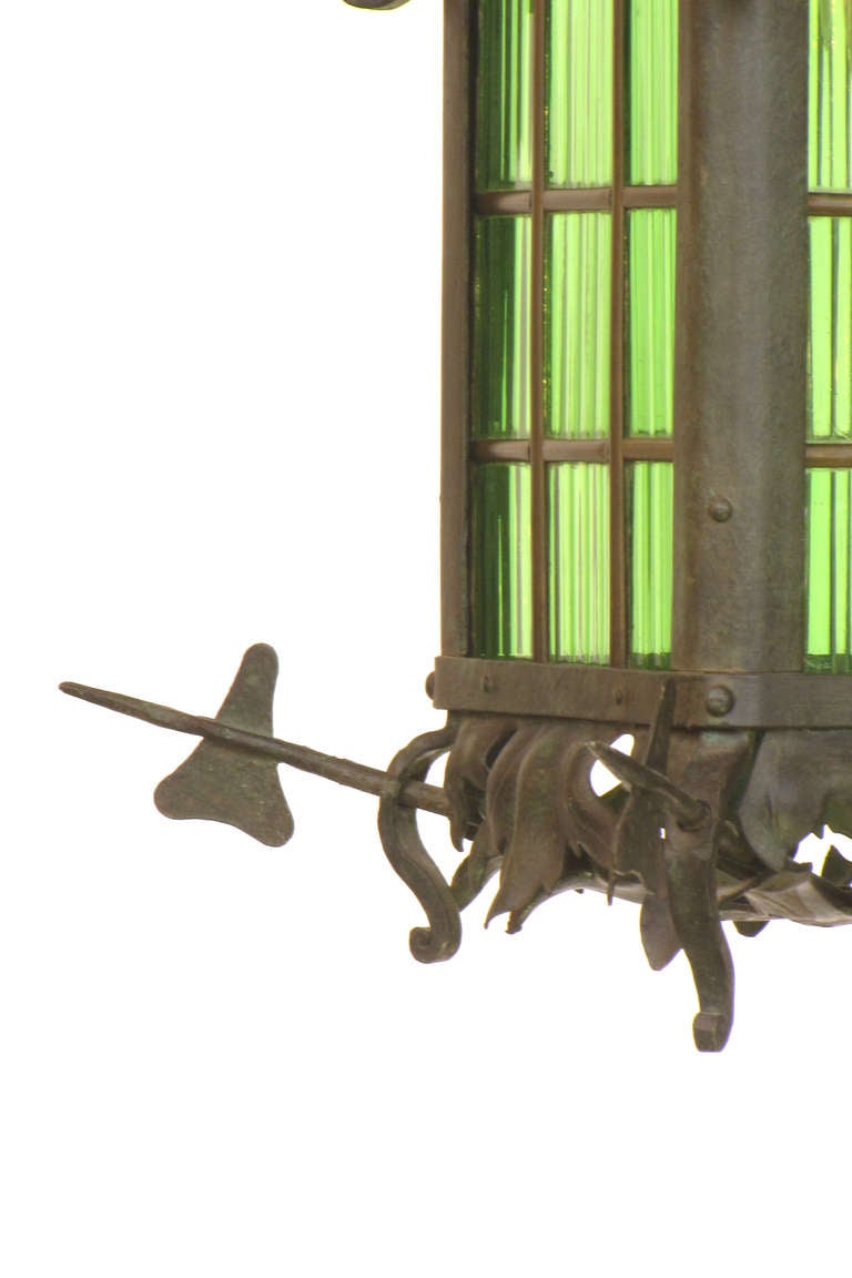 Iron and glass lantern with beautiful hand crafted metalwork.  The metal is wrought iron with a green patina.  the original glass is green with linear texture.  The lantern has a latching door showing fine construction on the frame and glass panes.