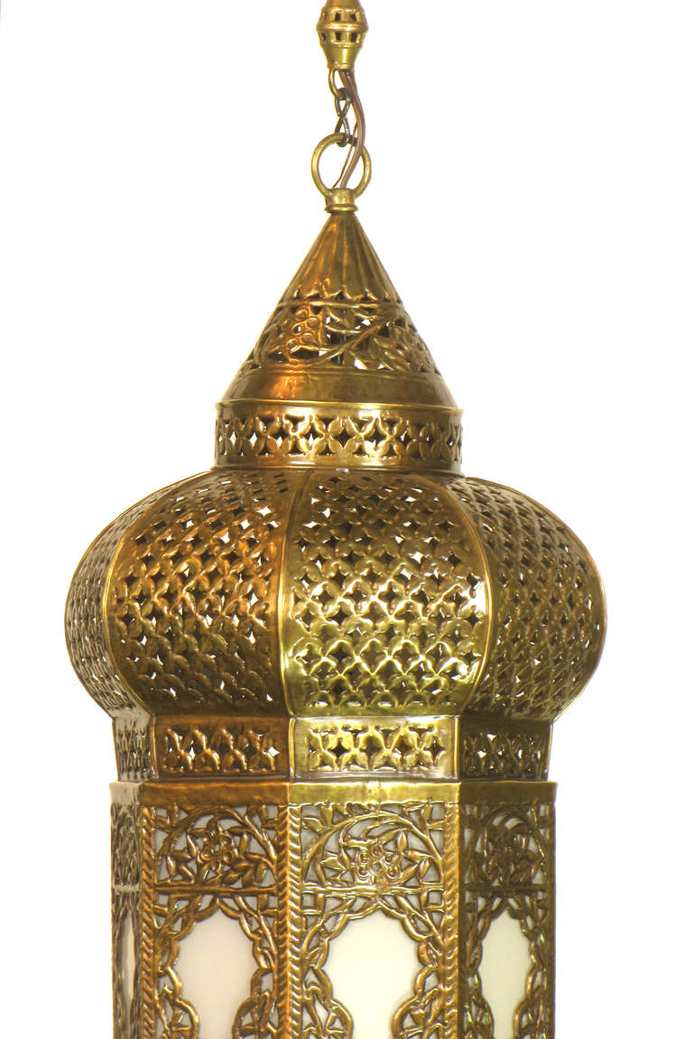 An ornate moroccan lantern with intricate punched metal designs on the panels and body of the lantern.  White glass on each of the eight panels.   height includes ornate original chain, and can be shortened to approximately 36