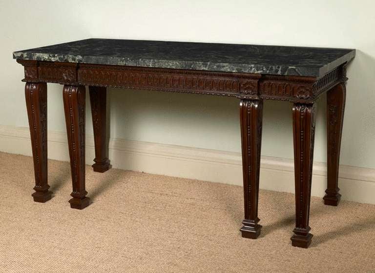 UNUSUAL CARVED MAHOGANY SIDE TABLE with marble top, the frieze with a series of conjoined lancets, between a top moulding of stiff leaf within a lappet on a punched ground, and the lower, a variant of egg and dart, the legs headed by a double