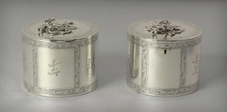 Engraved with pseudo-Chinese characters within rococo scrollwork, the flat covers with flower spray finials, one cover hinged, the other sleeved on. Marked on bases and covers. <br />
<br />
Signed, Inscribed, Dated: Marked on bases and covers, John