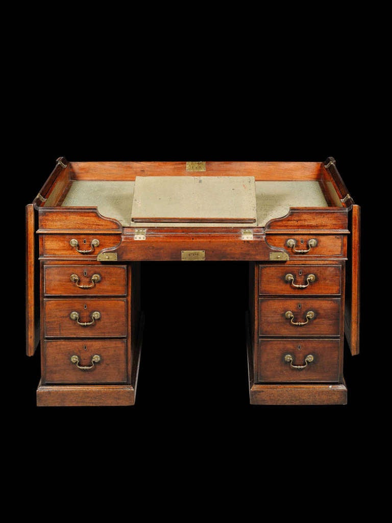 The rectangular top enclosed by a pair of hinged panels which fold out to rest against the sides, and a shaped section at the front which folds down, the interior with the original faded green baize lining, the central reading flap with detachable