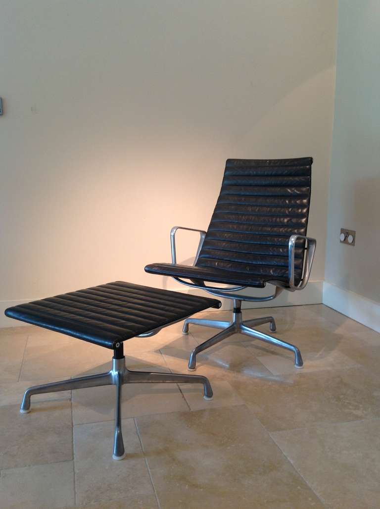 A circa -1980 Black leather and aluminium lounge chair and matching ottoman ..The frame cast with the numbers 938 139 and bearing a Herman Miller adhesive label to the base of the stool. the seat of the chair on revolving base.