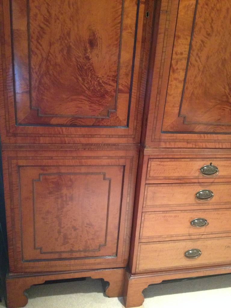 A superb quality and rare satinwood and rosewood cross banded wardrobe circa 1790. The four panel doors with applied moulding . The lower section with central bank of two short and three long drawers with oval floral embossed bail handles. The