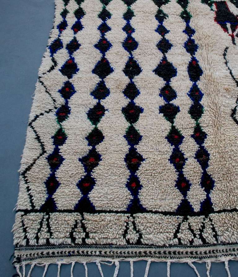 Vintage pile rug from the Azilal region. Strings of vertically placed lozenges and irregular lines typical for rugs from this region. The brightly colored accents are also often found on Azilal rugs.