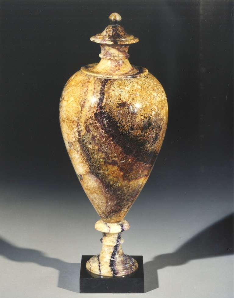 A fine early 19th century 'New Cavern Vein' Blue John urn having an ovolo body with stepped and waisted fixed lid, on a waisted circular base terminating in a square black marble socle. 

Literature: Trevor D. Ford, ‘Derbyshire Blue John’, 2005,