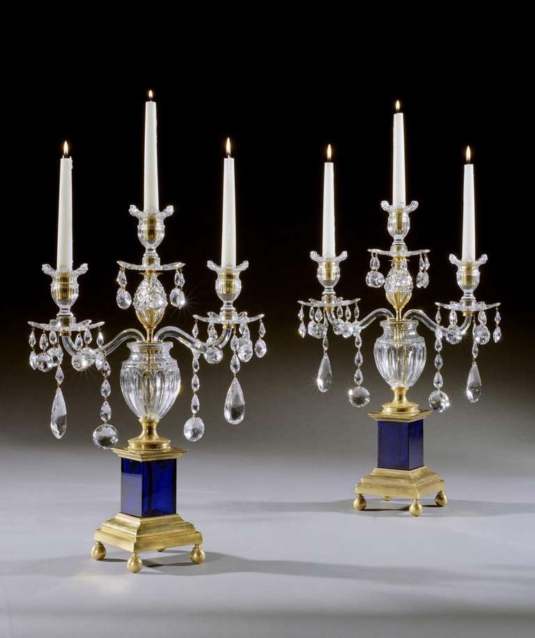 A fine quality pair of late 18th century cut glass three-light candelabra by Parker and Perry. Each having a fluted baluster vase with a centred column, issuing scrolled arms and a central stylised pine cone, headed by cut glass drip pans with drops
