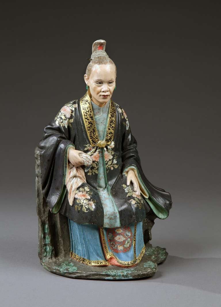 A rare pair of late 18th century ‘nodding head’ polychrome decorated figures of a mandarin and his female consort, retaining most of their original paint. The male figure is seated on rockwork and wears a bright yellow robe decorated with floral
