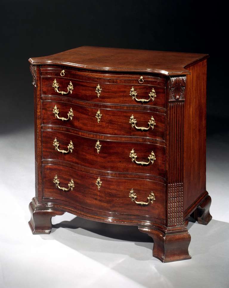 A fine mid 18th century Chippendale period carved mahogany chest of drawers of unusually small size in the manner of William Hallett, having a serpentine fronted moulded top with protruding corners above a brushing slide and four graduated drawers