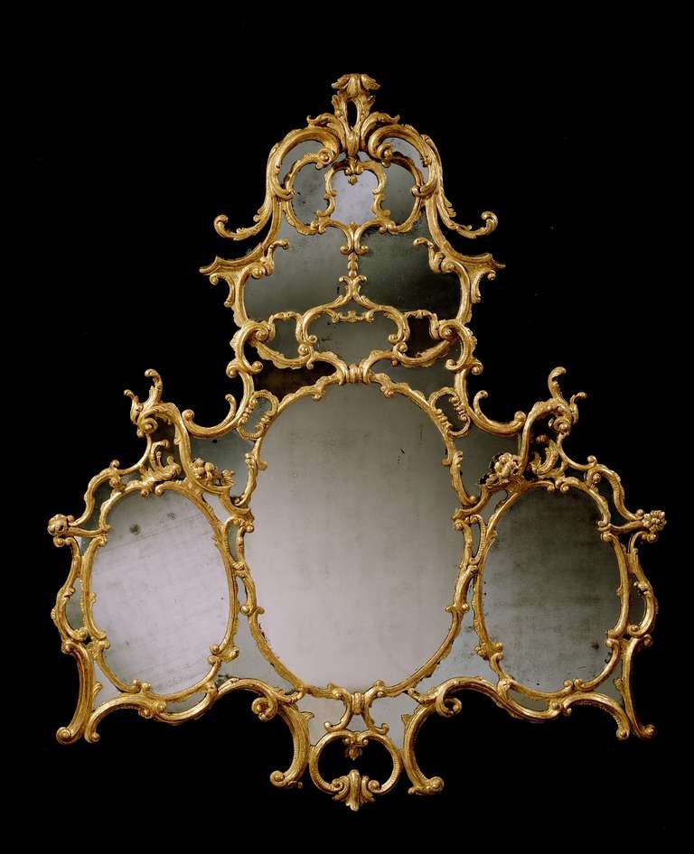 A fine mid 18th century Chippendale period carved overmantel border glass, retaining most of the original gilding and mirror plates. The arched upper plate divided by rococo tracery and surmounted by a foliate plume, with a central oval plate below,