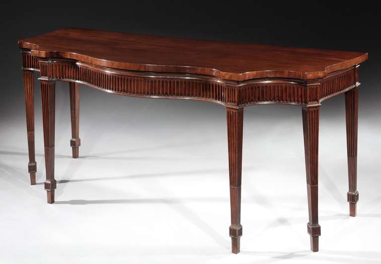A mid 18th century Chippendale period mahogany serpentine side table, having a finely figured top above a fluted frieze; on six square tapering fluted legs with oval paterae headings and terminating in blocked toes. 

Provenance: Hotspur Ltd.,