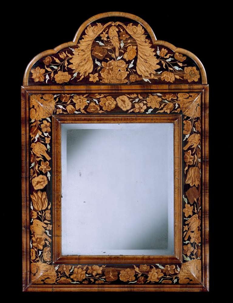 A late 17th century marquetry cushion mirror in the manner of Thomas Pistor, having an 18th century replaced bevelled mirror plate within a crossgrain moulded edge and cushion moulding finely veneered in floral and bird marquetry of various timber