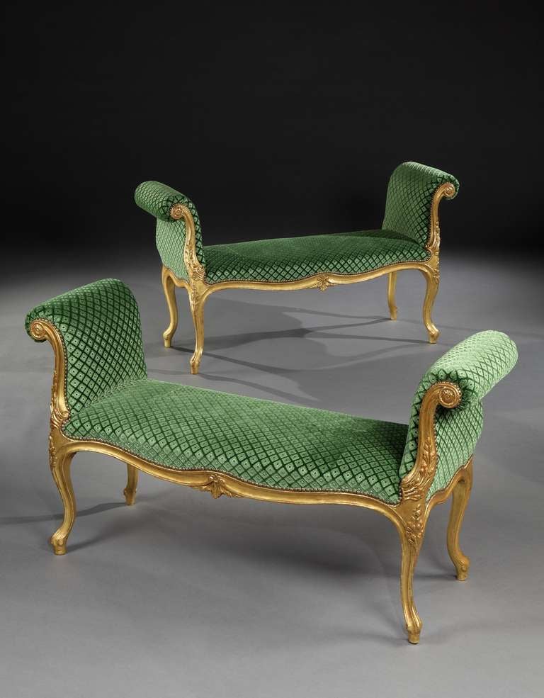 An impressive pair of mid 18th century Chippendale period carved giltwood window seats of generous proportions, each having a serpentine fronted seat upholstered in green silk gaufrage velvet, upright outscrolled arm supports faced with carved
