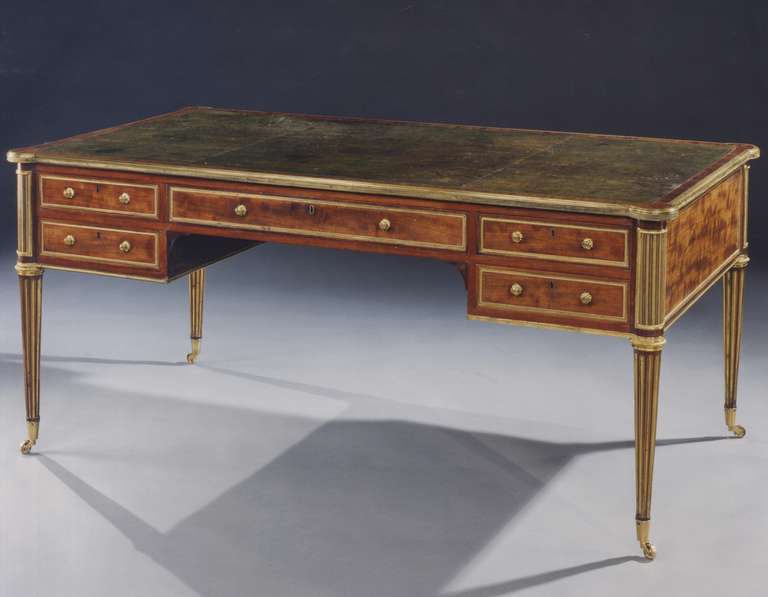 An outstanding quality early 19th century mahogany and brass mounted writing table, retaining the original gilt tooled green Morocco leather insert, crossbanded with mahogany and having protruding corners edged with a chased gold lacquered brass