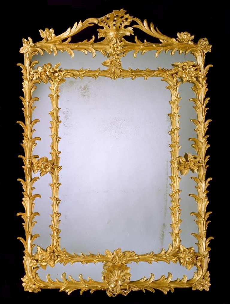An unusual late 18th century gilt composition upright rectangular border glass mirror retaining all the original mirror plates and most of the original gilding within a frame of palm fronds and floral ties having a shaped pierced cresting centred by