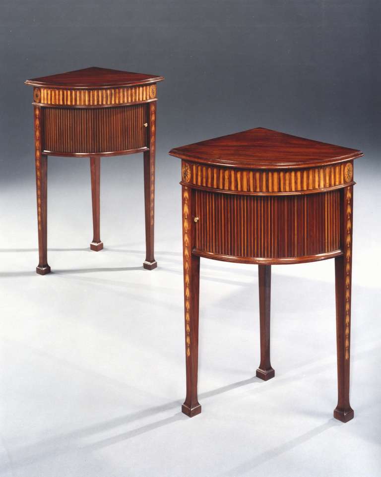 A rare pair of late 18th century Adam period mahogany and sycamore bedside cupboards in the manner of Mayhew and Ince, having a solid moulded top above a mahogany and sycamore veneered frieze simulating fluting and a tambour door below with brass