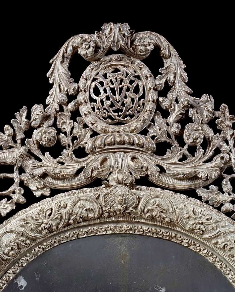 An important and extremely rare late 17th century silvered mirror in the manner of Daniel Marot. The 18th century replacement oval mirror plate within a moulded frame profusely carved with sprays of oak leaves, acorns and flower heads on a pounced