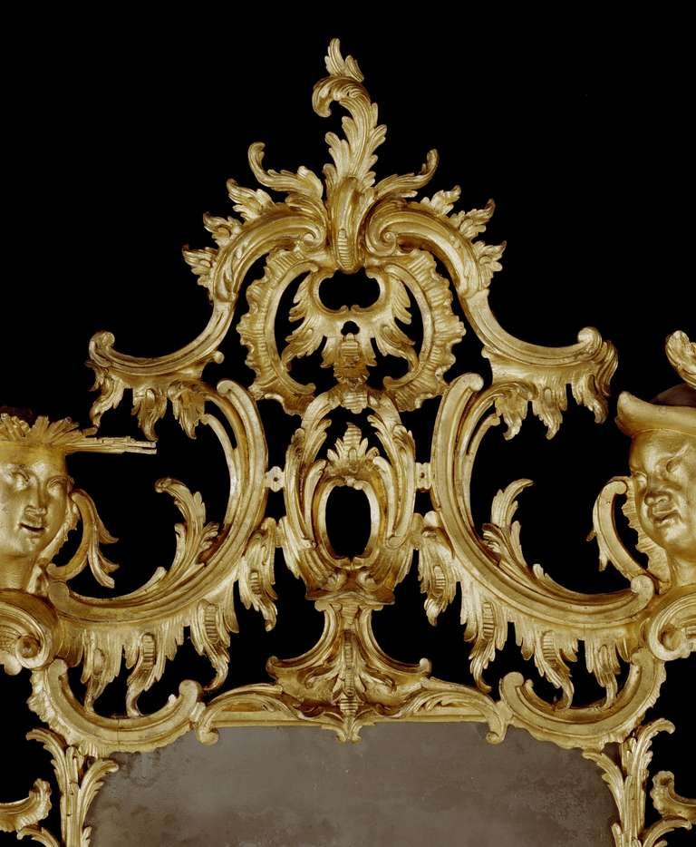 A rare and possibly unique mid-18th century carved giltwood mirror in the manner of Matthias Lock, retaining its original oil gilding and large original rectangular mirror plate, having arched cresting with pierced foliate carving around a rocaille