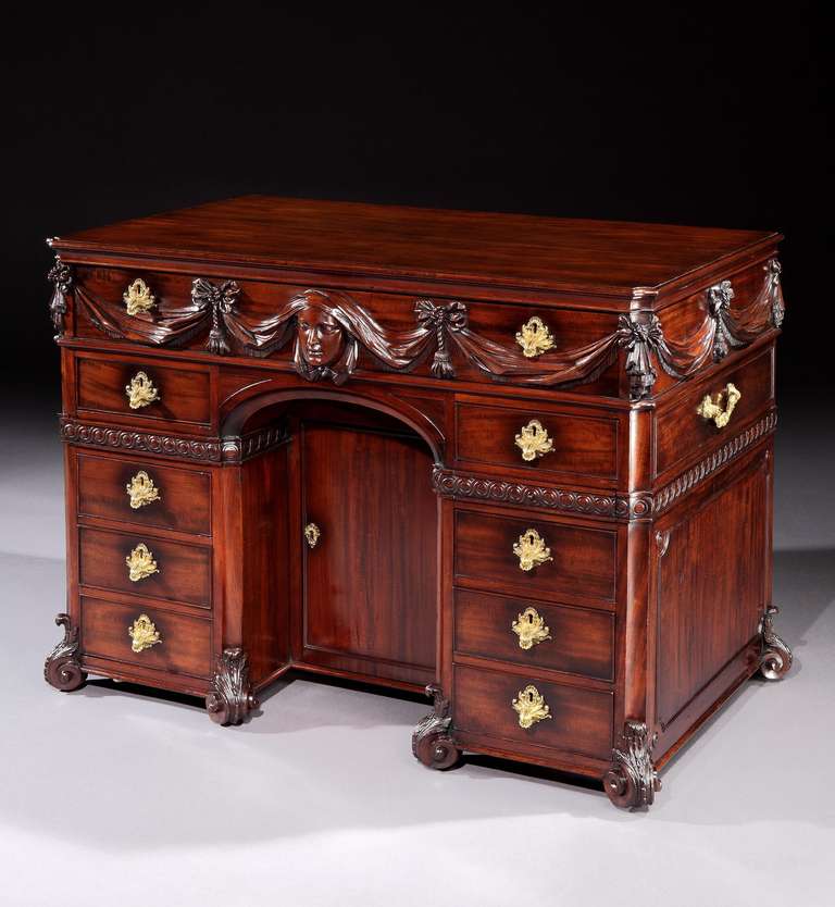 An important and rare mid 18th century Palladian period carved mahogany kneehole writing desk, having a rectangular top with moulded edge above a frieze with long single drawer applied with exquisitely carved drapes and tassels centred by a female