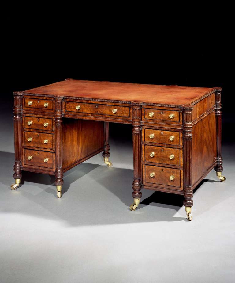 A fine early 19th century mahogany pedestal desk attributed to Gillows, having a rectangular top with lobed corners, crossbanded in mahogany and lined with gold tooled faded red leather, above a frieze with one long and two short drawers above three