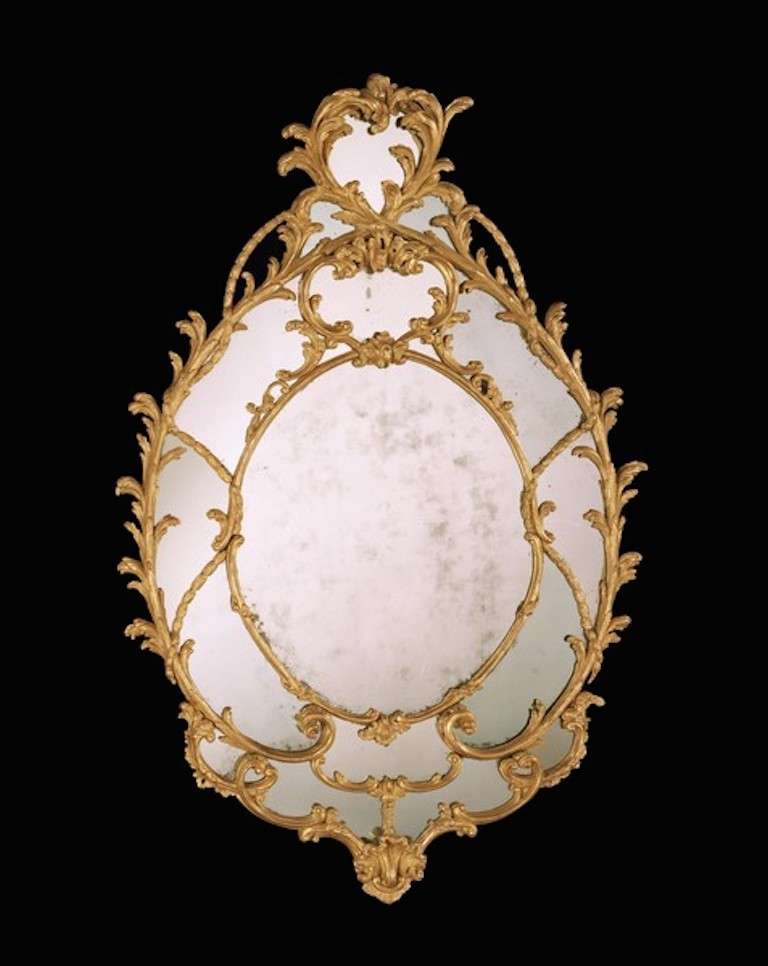 An exceptional mid 18th century Chippendale period carved giltwood oval border glass mirror, having a replaced 18th century mirror plate within an oval inner frame finely carved with entwined scrolls and leaves and trailing husks forming the