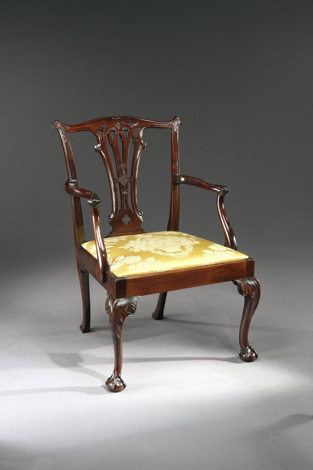 A pair of unusually large mid-18th century carved mahogany armchairs in the manner of Thomas Chippendale, each having a serpentine shaped crest rail, exceptionally fine carved acanthus corners and a pierced splat carved with C-scrolls and having out