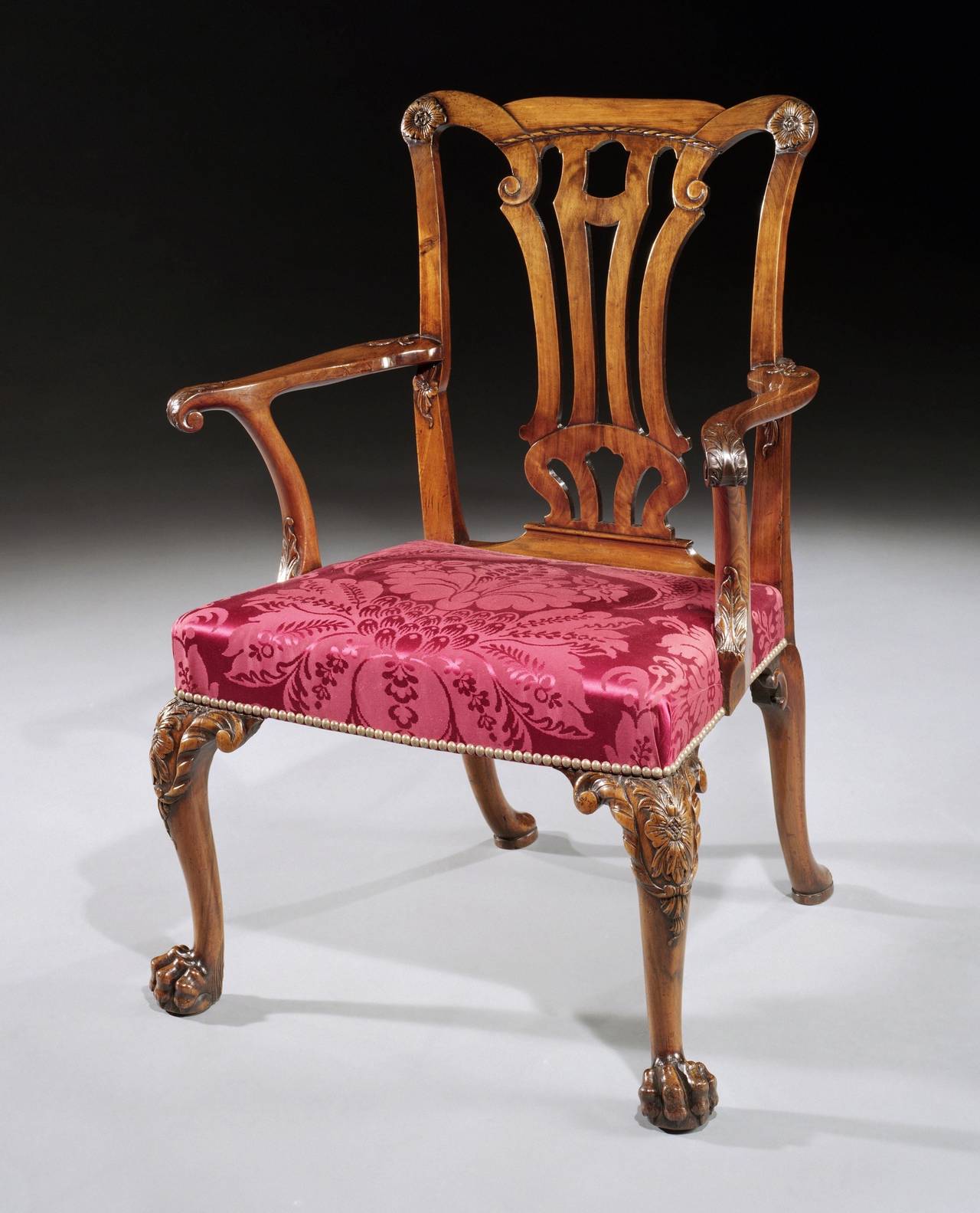 A set of 14 mid-18th century carved walnut dining chairs comprising 12 side chairs and two armchairs, each having a yoke shaped back and shaped uprights with a pierced vase shaped splat and applied with carved flora paterae and rope ornament, and