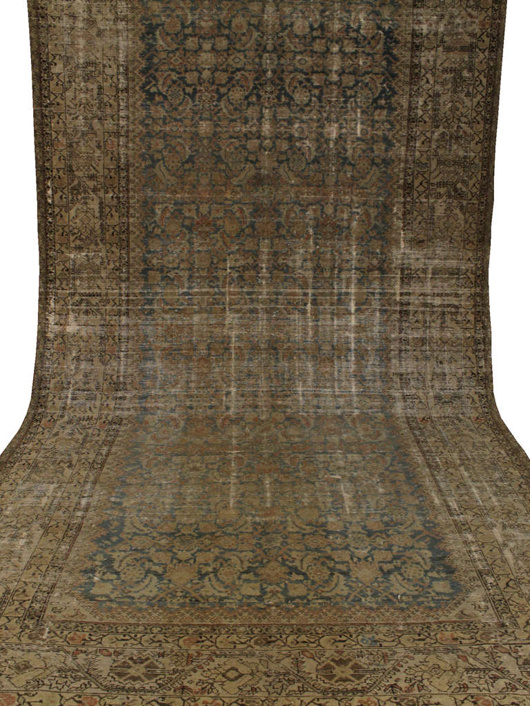 This long Malayer features an all over geometrical design in light colors that are partially faded, like cool contemporary rugs. Blue and soft red-brown ground color with ivory and blue in the borders.