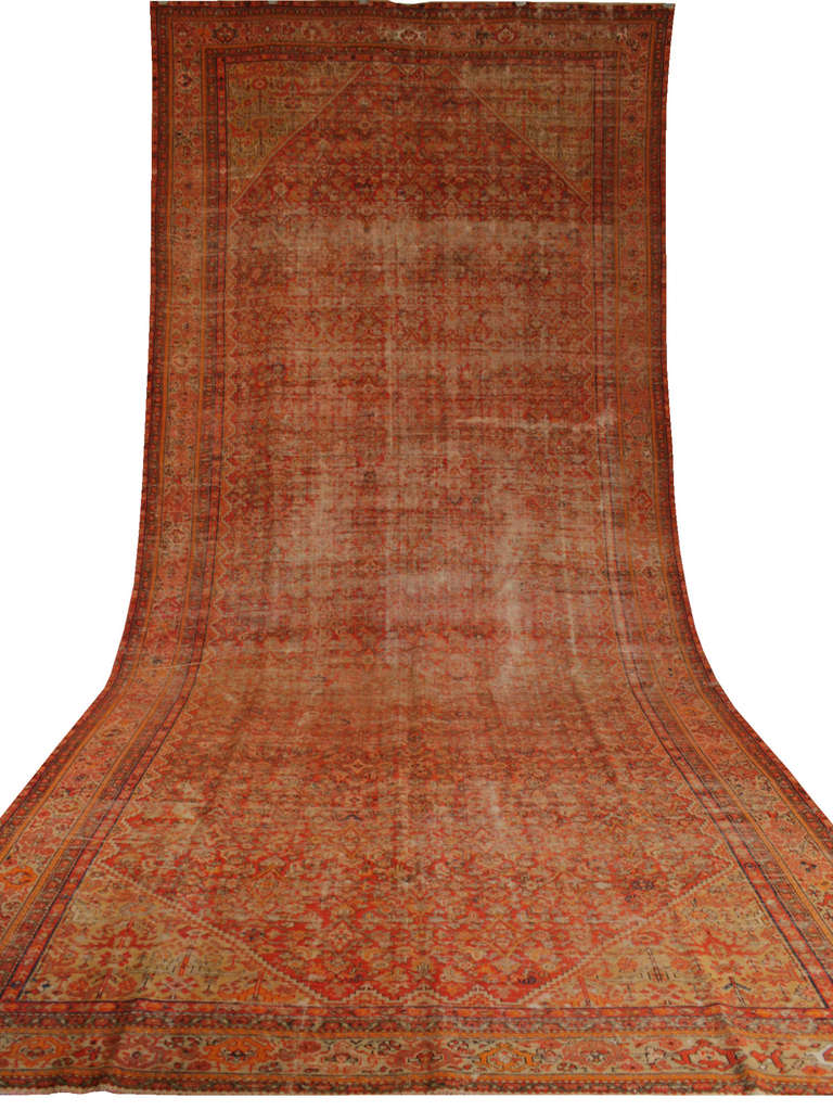 This long Malayer features an all over geometrical design in light colors that are partially faded, like cool contemporary rugs. Red and orange ground color with ivory and blue in the borders.