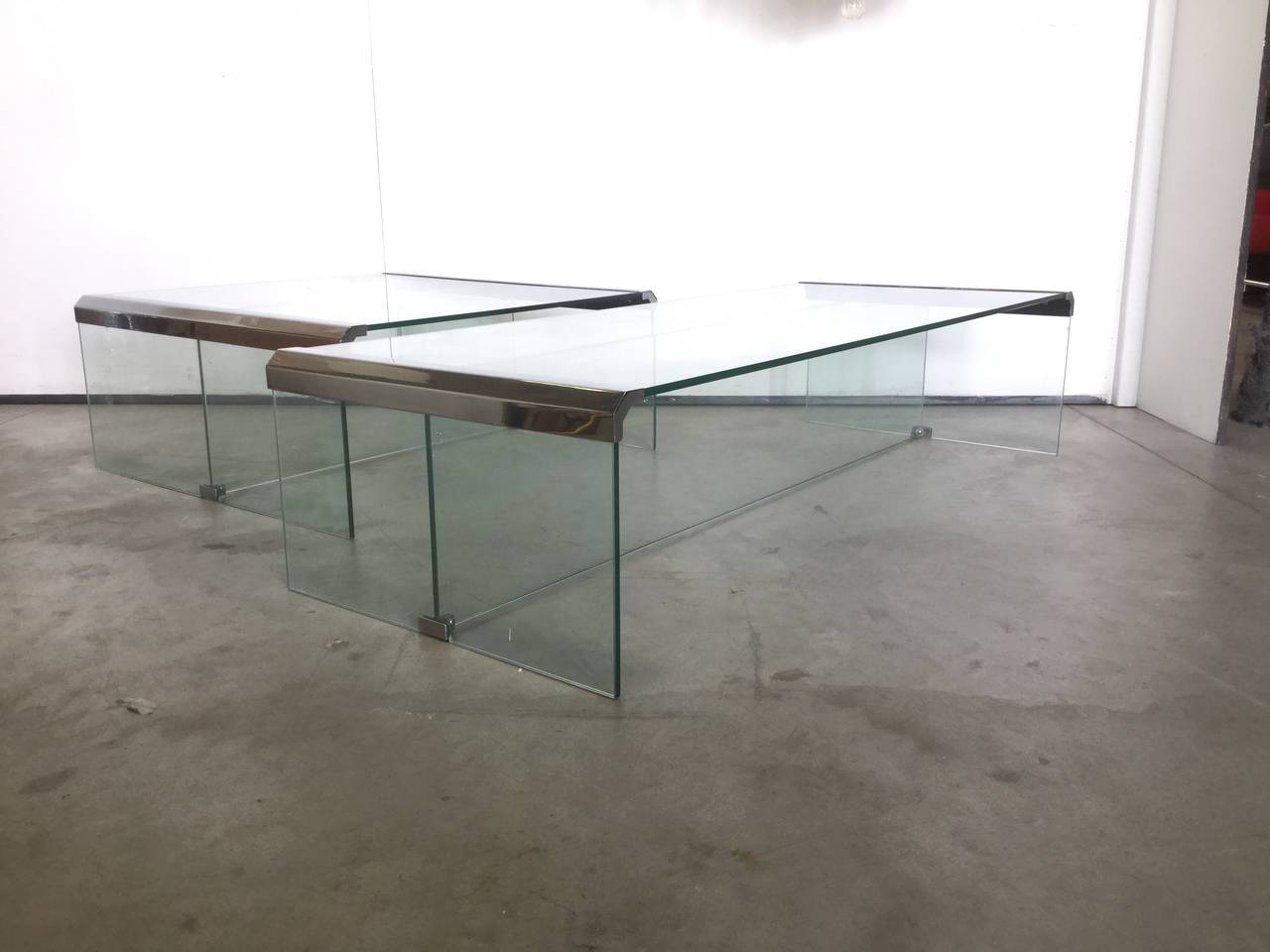 Beautiful set of two coffee tables in different size: The little one is cm 70 x cm 70 x H cm 45, the big one is cm 70 x cm 120 x H cm 45.
The tables are made of thick glass plates linked by chrome metal connections.
Manufactured by Fontana Arte in