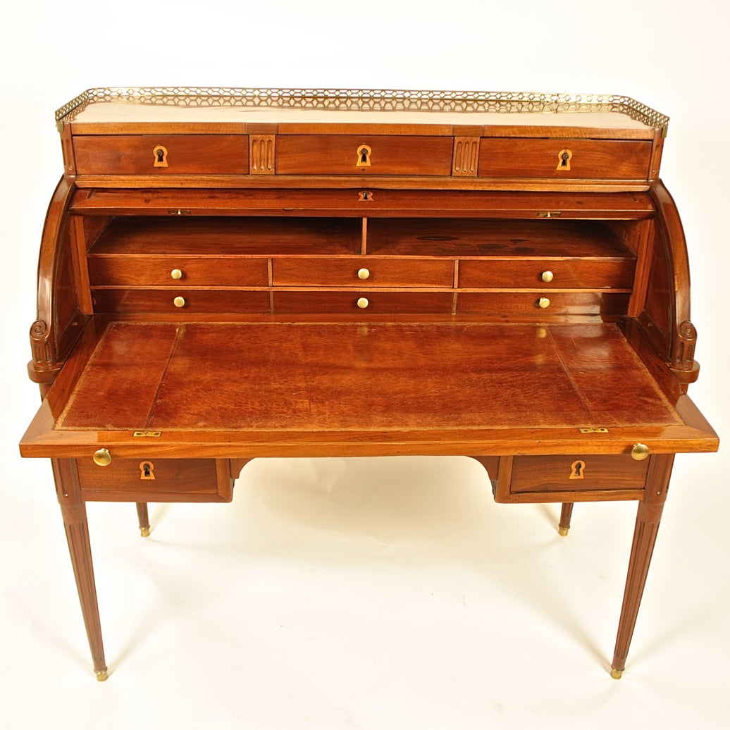 An elegant freestanding mahogany roll top desk attributed to Godefroy Dester (maitre 1774).
The rectangular top surrounded by a pierced brass gallery, above three drawers, the roll-top opening to reveal a sliding leather writing surface surmounted