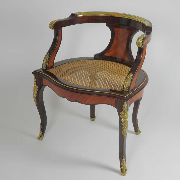 A very rare and fine kingwood ’Fauteuil de Bureau' with a rounded back, its top rail inlaid with brass moulding above a middle concave shaped splat. Arm endings decorated with ormolu mounted acanthus leaves. The frame of the caned seat surrounded by