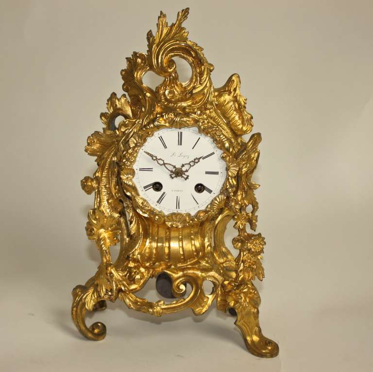 A fine ormolu mantel clock of asymmetrical rococo form. The enamel dial with Roman numerals inscribed with 'Lou Leysz a Nancy'. Dial surmounted by foliate scrolls and floral pendants. silk suspension, clock strikes at half-hour and hour.