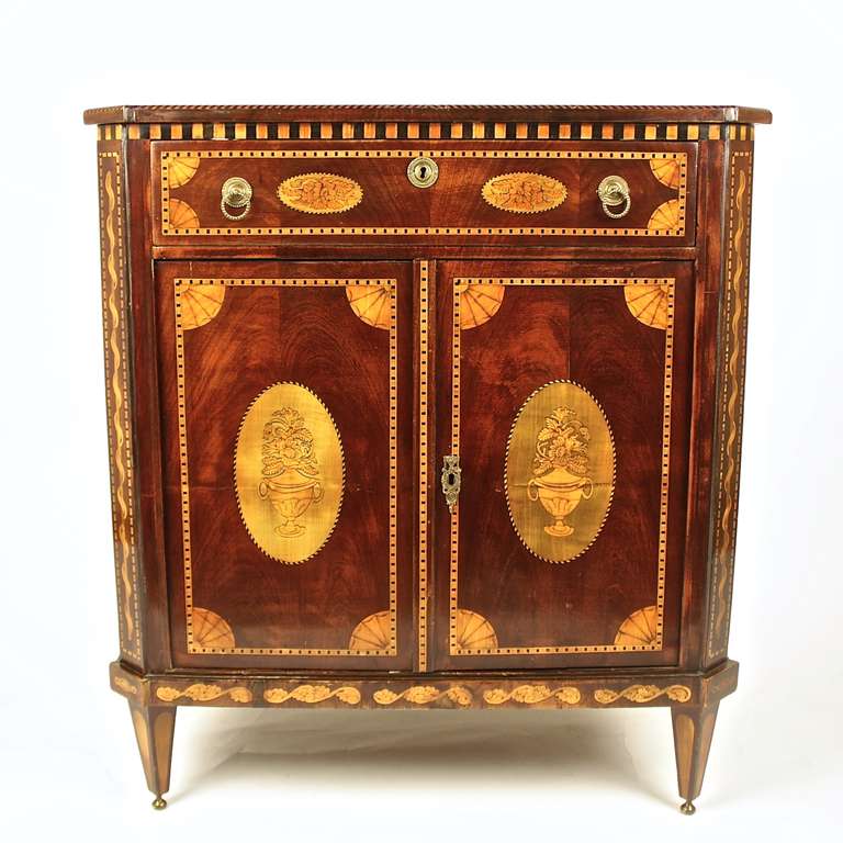 A one drawer and two-paneled door cabinet of Dutch origin, in the manner of Matthijs Horrix (1735-1809). With prominent central oval medallions on top, drawer, doors and sides, inset with vase motifs, fans or flowers within a banded border. The