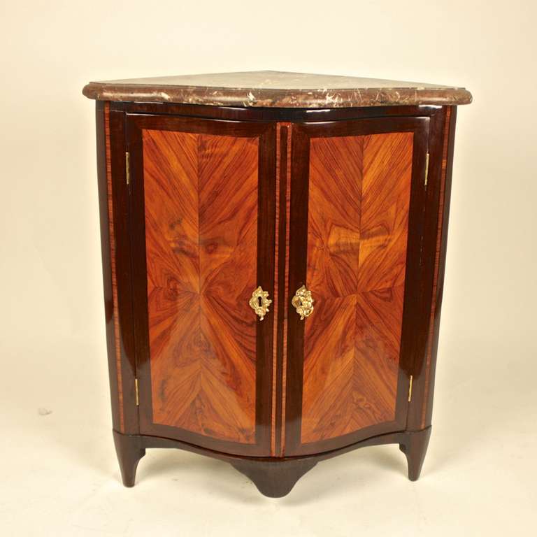 An 18th century Louis XV marquetry Kingwood encoignure or corner cabinet with bombe shaped two quartered-veneered panel doors and fitted rouge marble top. This item features simple shapes by using high quality material such as kingwood veneer on an