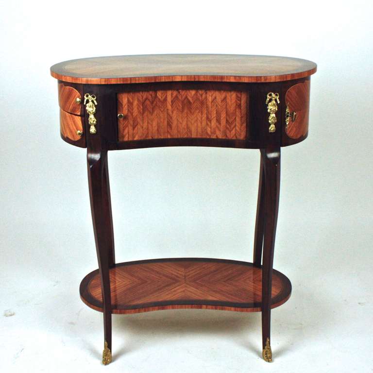 A Centre Table of kidney-shaped form, the frieze with a tambour slide revealing three drawers, with two sliding compartments and and one door compartment, with canted corners and gilt-bronze mounts, on slender cabriole legs joined by a kidney shaped