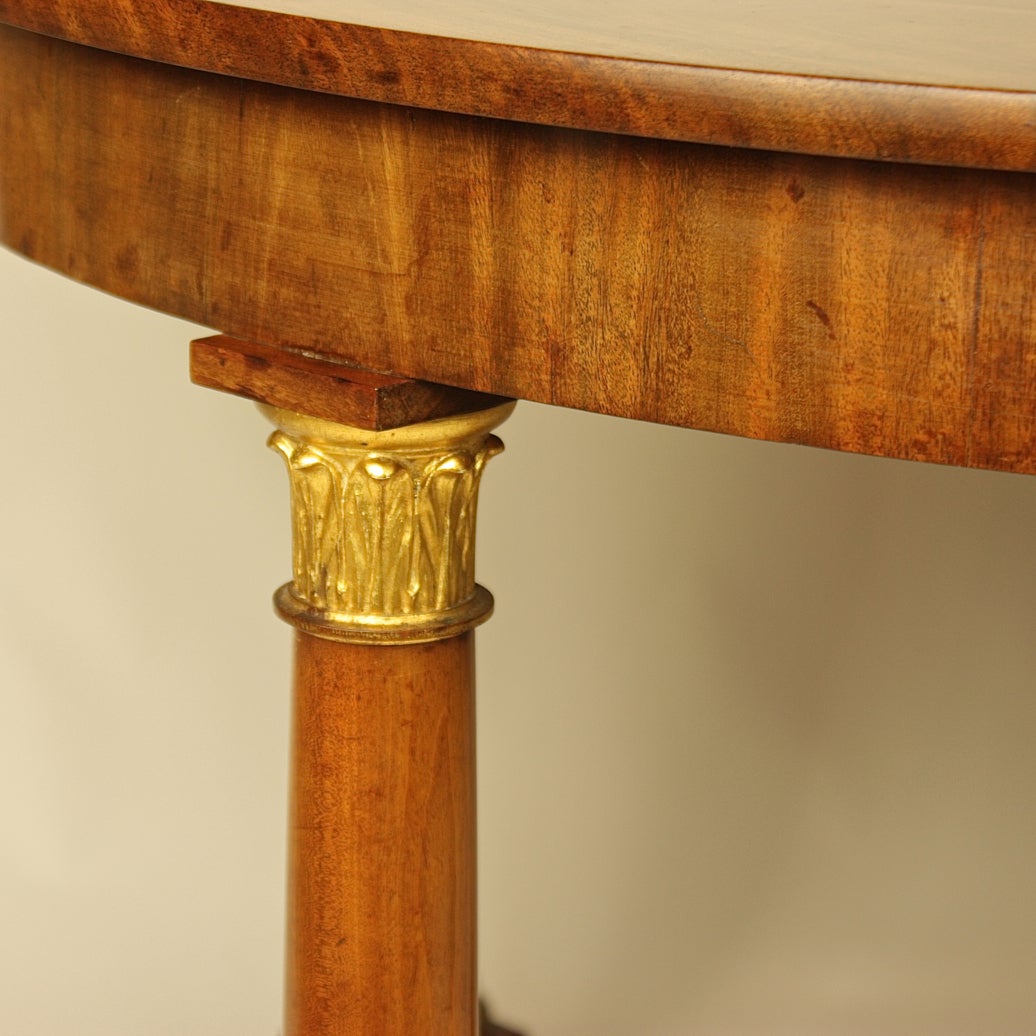 An Austrian early 19th century round Biedermeier coffee table raised on free standing columns with gilded foliate capital and base, on a quadripartite plinth. Walnut veneer on pinewood construction.