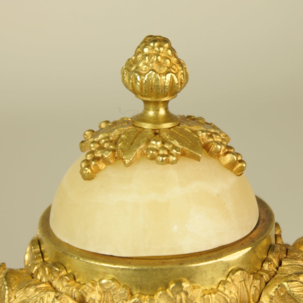 Very fine pair of Louis XVI gilt bronze and white alabaster cassolettes of ovoid form. A grape vine finial crowns the top, revealing an enclosed gilt bronze cast inverted candlestick below.
The lower section is a stepped and fluted circular base
