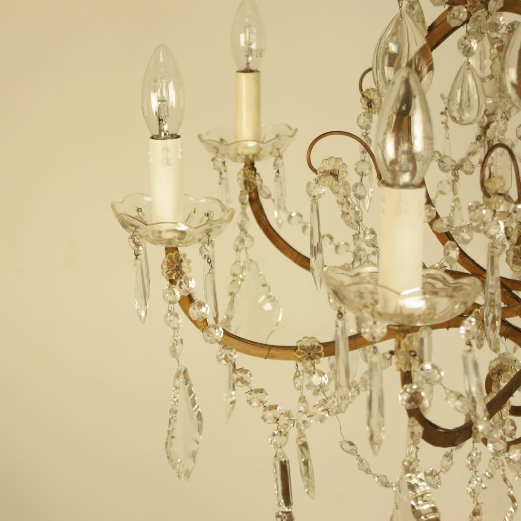 A twelve-light pear-shaped chandelier issuing four bronzed iron arms in the upper section and eight arms in the lower section, richly hang with pendeloques, icicles, ball finial and central crystal-cut obelisk.