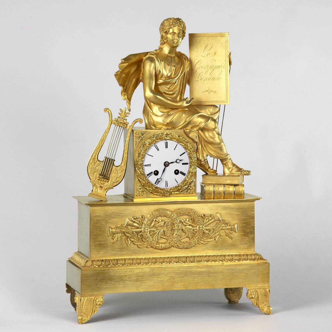 A very fine Empire ormolu figural mantel clock of eight day duration, with enamel dial and Roman numerals and a pair of blued steel hands for the hours and minutes. The movement with silk thread suspension, anchor escapement, striking on the hour