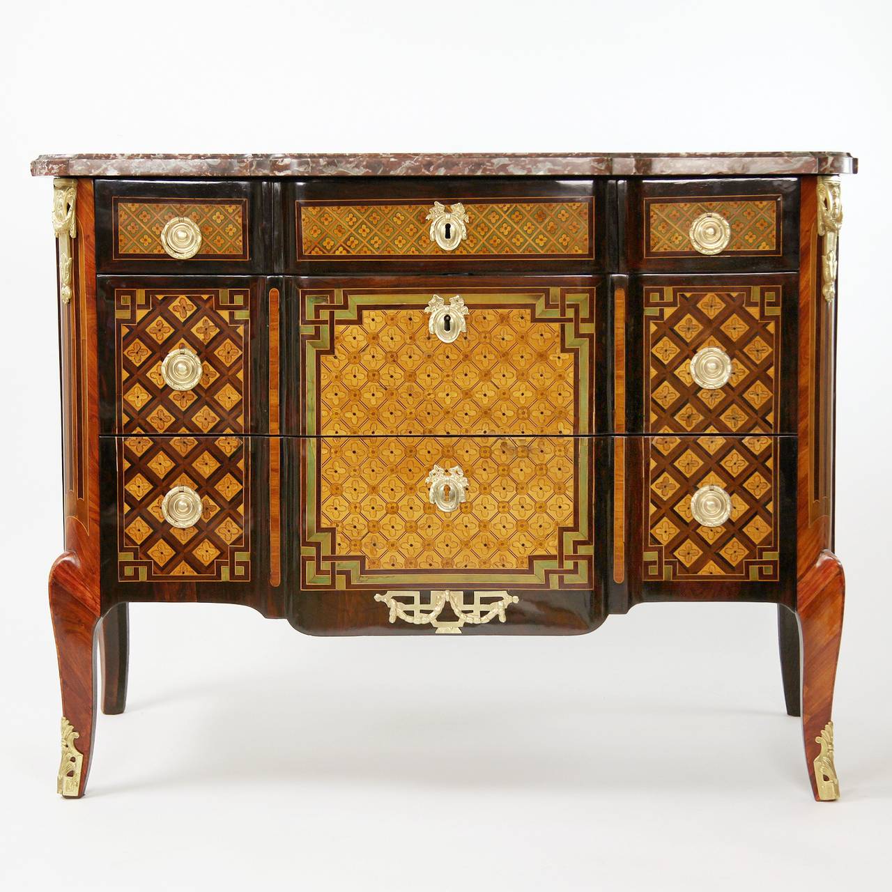 A magnificent gilt bronze mounted kingwood and amaranth parquetry commode with a shaped moulded mottled rouge marble top with rounded corners, above a frieze drawer (devided into three) and two long drawers of break-front form inlaid with trellis