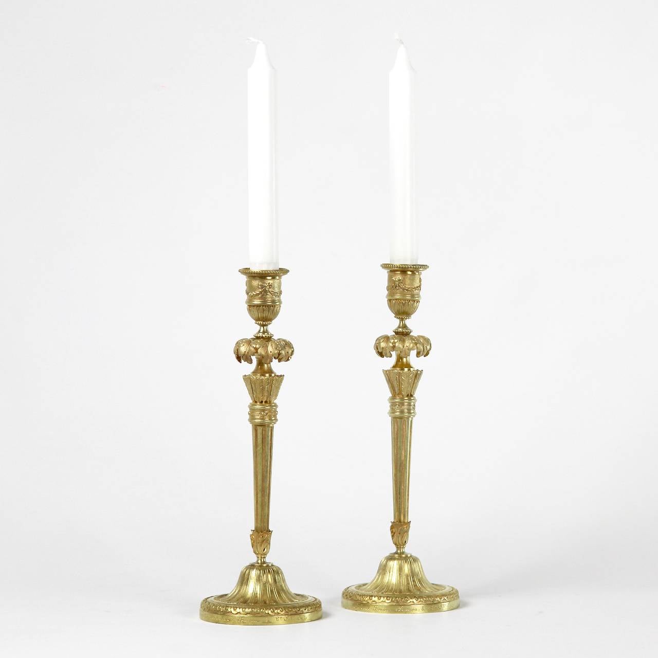 A pair of gilt bronze candlesticks inscribed 'Thiebaut Freres. Fumiere & C S Paris'. Thiébaut Frères was a Parisian foundry of the late 19th century devoted to works of art. 
The pair of gilt-bronze candle sticks in Louis XVI style, the candle