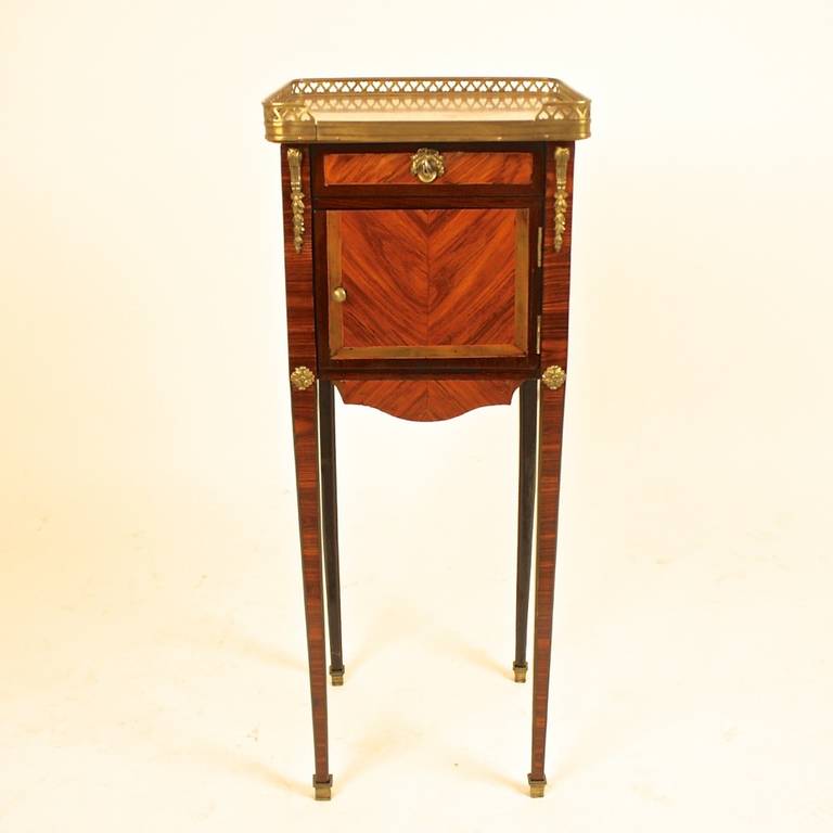 Of square form, with an inset galleried Breche d'Alep marble top above a skirted front, with one drawer and a paneled door compartment, on slender tapering legs with gilt bronze sabots.