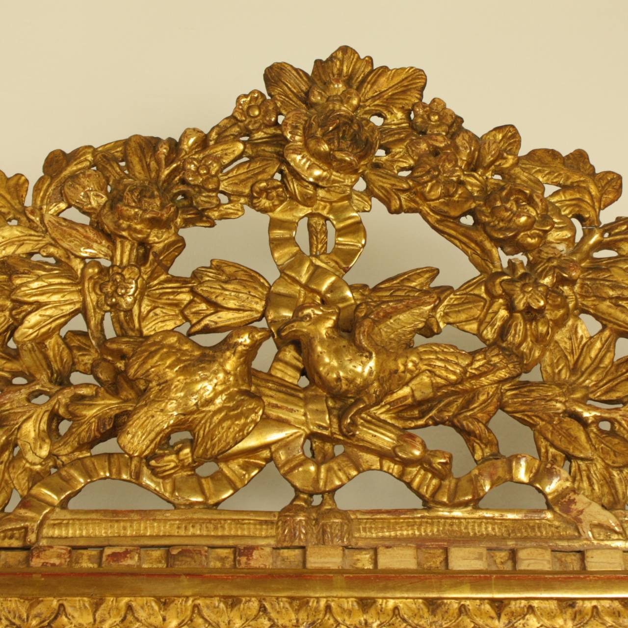 A fine 18th century Louis XVI giltwood mirror, now fitted with a later bevelled mirror plate., the rectangular frame carved with a twisted ribbon and  beadwork. With a pierced leafy cresting above a pair of doves, quivers, foliage and flowers,